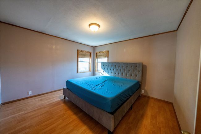 Bedroom with crown molding, wood finished floors, and baseboards | Image 16