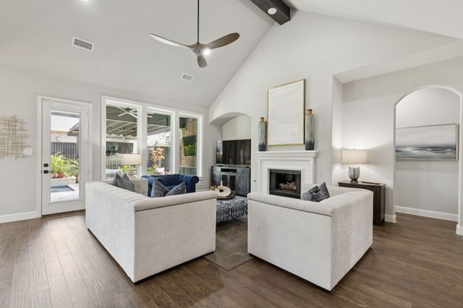 Living room featuring a glass covered fireplace, beam ceiling, a ceiling fan, high vaulted ceiling, and dark wood finished floors | Image 10