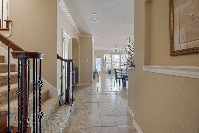 Hallway featuring light tile patterned flooring, baseboards, ornamental molding, and stairs | Image 19