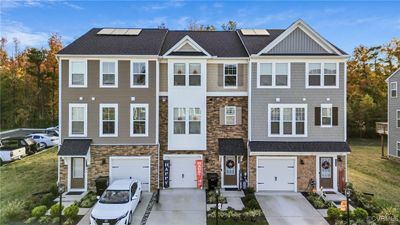 Townhome / multi-family property featuring a front yard and a garage | Image 2