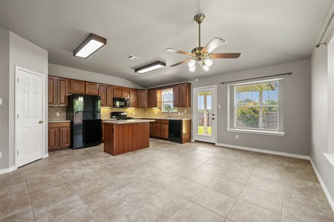 Kitchen with black appliances, tasteful backsplash, light countertops, and a center island | Image 7