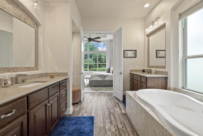 Bathroom with connected bathroom, a ceiling fan, a relaxing tiled tub, two vanities, and wood finished floors | Image 18