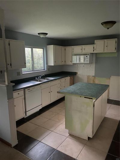 Kitchen with dishwasher, white cabinetry, light tile patterned floors, and sink | Image 3