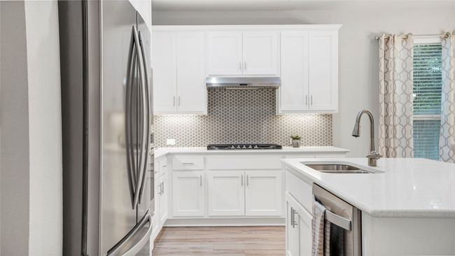 Kitchen featuring exhaust hood, backsplash, a sink, stainless steel appliances, and an island with sink | Image 4