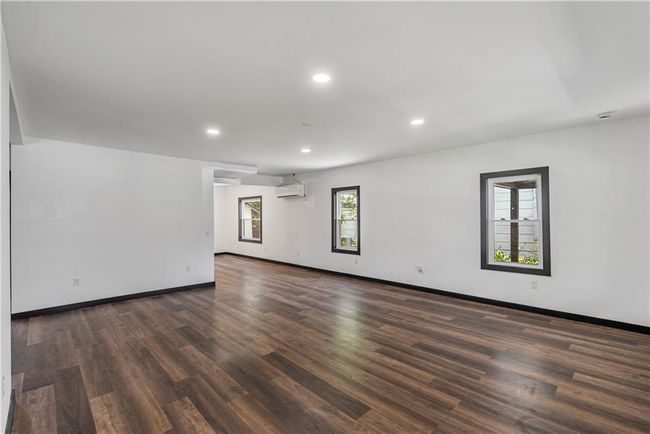 Living room featuring dark wood-style floors, recessed lighting, baseboards, and a wall unit AC | Image 12