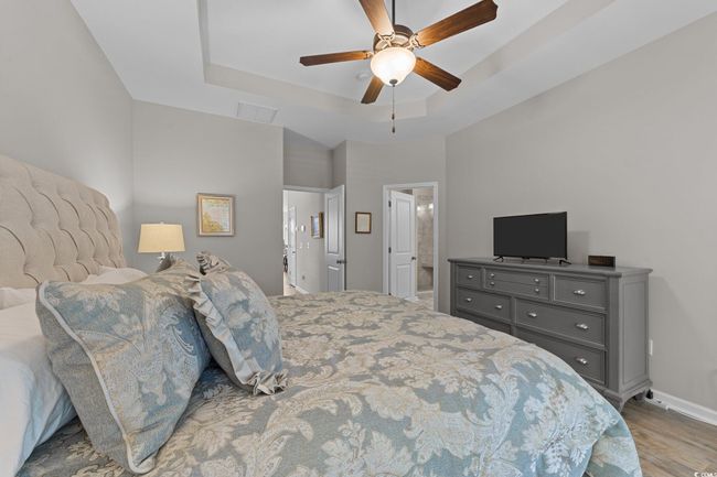 Bedroom with wood finished floors, a raised ceiling, baseboards, ceiling fan, and ensuite bathroom | Image 16