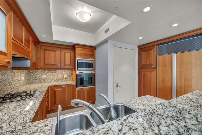 Kitchen featuring a sink, visible vents, decorative backsplash, built in appliances, and brown cabinetry | Image 24