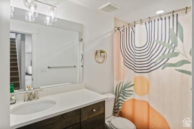 Full bathroom featuring toilet, vanity, curtained shower, and visible vents | Image 25