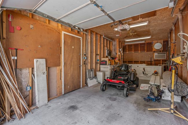 Garage featuring a garage door opener, a workshop area, and an AC wall unit | Image 30