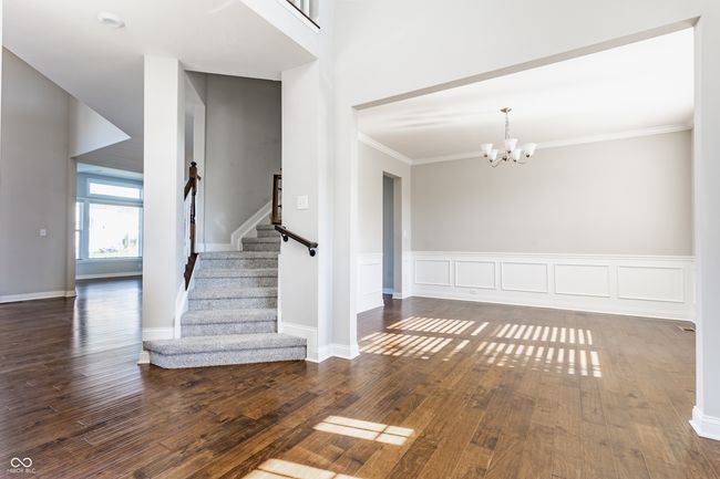 foyer featuring stairway, a notable chandelier, wood finished floors, and ornamental molding | Image 9