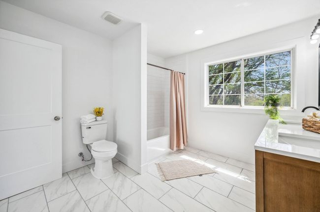 Bathroom with shower / tub combo, vanity, toilet, visible vents, and marble finish floor | Image 23