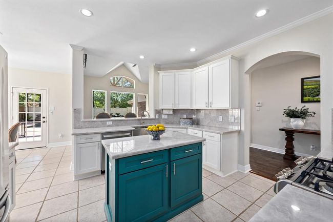 Stunning kitchen includes white cabinetry, illuminato quartzite counters and backsplash, and SS appliances. | Image 14