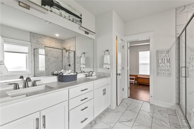 Bathroom featuring double sink, tile floors, a shower with door, and large vanity | Image 24