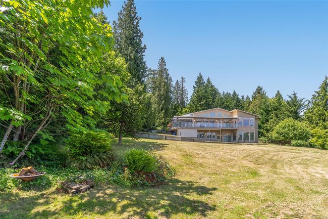 View of green lawn featuring a view of trees and a deck | Image 61