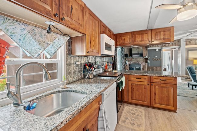Kitchen featuring white appliances, backsplash, sink, light hardwood / wood-style flooring, and light stone counters | Image 13