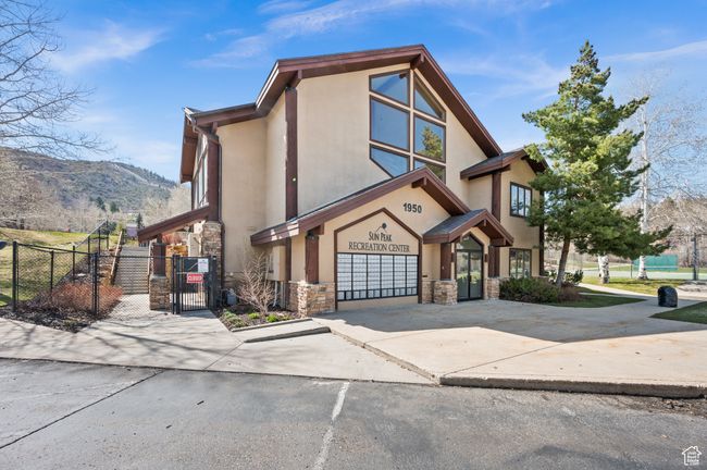 Clubhouse: View of front facade with a gate, stone siding, concrete driveway, fence, and stucco siding | Image 35
