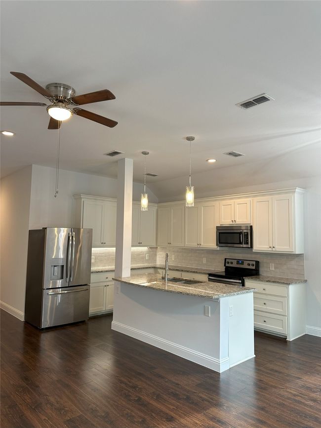 Kitchen featuring stainless steel appliances, backsplash, light stone countertops, white cabinetry, and recessed lighting | Image 8