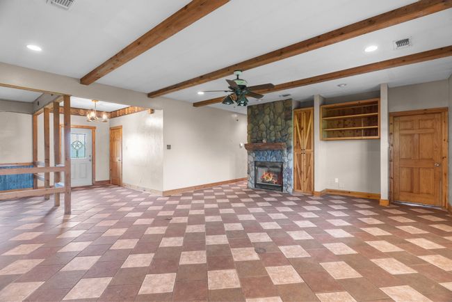 Unfurnished living room featuring baseboards, recessed lighting, visible vents, beam ceiling, and ceiling fan with notable chandelier | Image 20