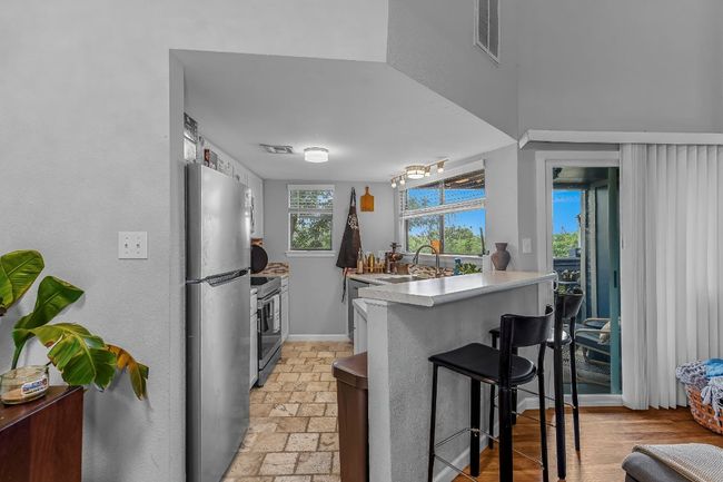Kitchen with stainless steel appliances, a sink, a kitchen bar, a peninsula, and light countertops | Image 5