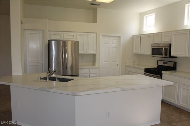 Kitchen with appliances with stainless steel finishes, a sink, and white cabinetry | Image 9