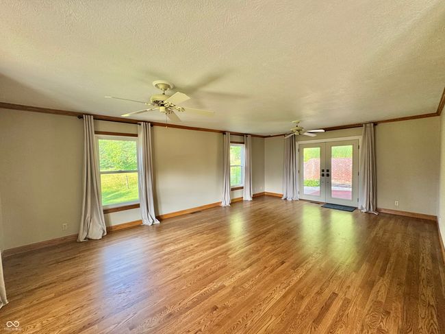 unfurnished room featuring french doors, light wood-style flooring, ceiling fan, crown molding, and a textured ceiling | Image 47