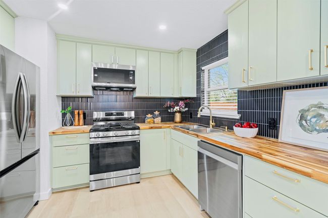 Kitchen featuring appliances with stainless steel finishes, butcher block counters, tasteful backsplash, and light wood-style floors | Image 12
