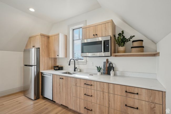 Kitchen with modern cabinets, appliances with stainless steel finishes, vaulted ceiling, open shelves, and a sink | Image 37