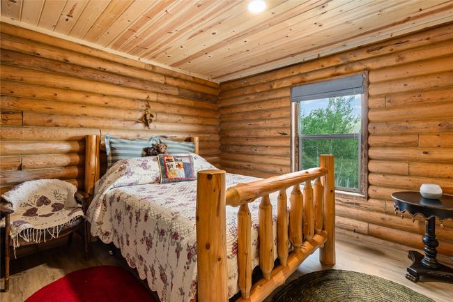 Bedroom featuring wood finished floors, wooden ceiling, and rustic walls | Image 17