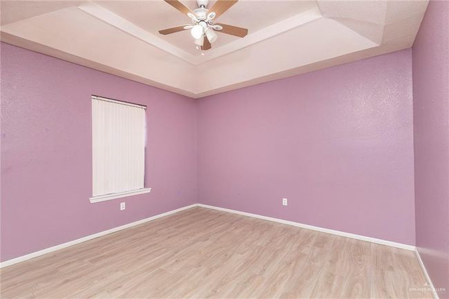 Unfurnished room with a tray ceiling, light wood-style floors, and a ceiling fan | Image 16