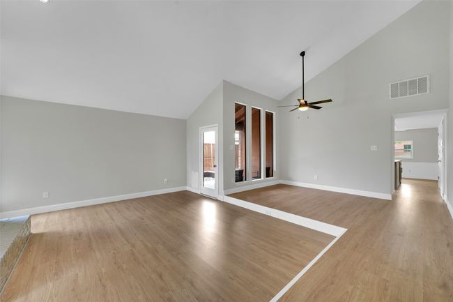 Unfurnished living room with high vaulted ceiling, wood finished floors, and ceiling fan | Image 4