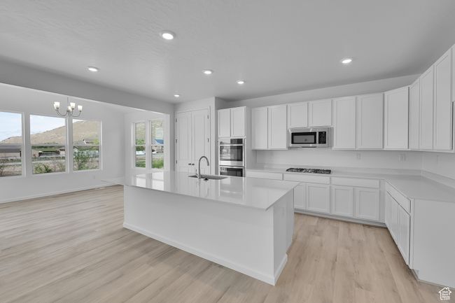 Kitchen with stainless steel appliances, recessed lighting, light wood finished floors, light countertops, and white cabinets | Image 7
