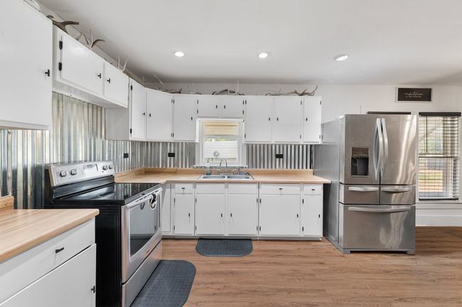 Kitchen with appliances with stainless steel finishes, a sink, white cabinetry, and light countertops | Image 8