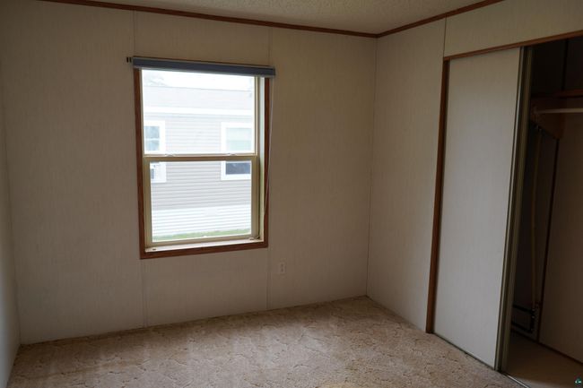 Unfurnished bedroom with carpet floors, crown molding, a closet, and a textured ceiling | Image 18