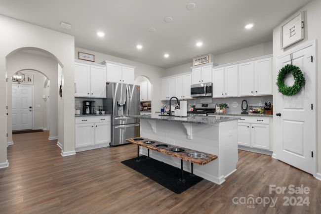Modern kitchen features, Butler's Pantry on right of refrigerator, walk-in pantry has wreath on the door and new shelving. Dog feeding station does not convey! Far left is foyer leading to the front entrance. | Image 11