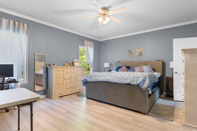 Bedroom with light wood-type flooring, ornamental molding, and a ceiling fan | Image 11