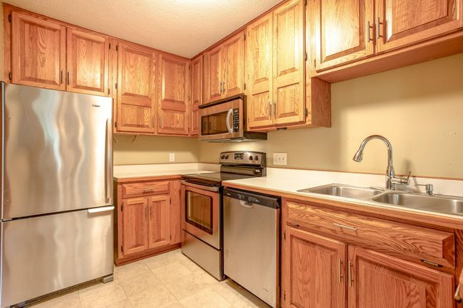 Stainless-steel fridge, oven, microwave, and dishwasher are neatly tucked into warm oak cabinetry with plenty of storage. | Image 10