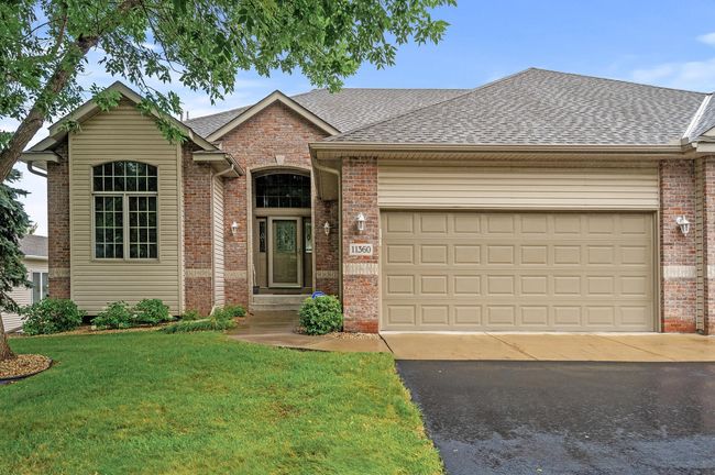This custom built home features a timeless brick front, architectural details, covered front porch, gutters, and newer asphalt driveway. | Image 5