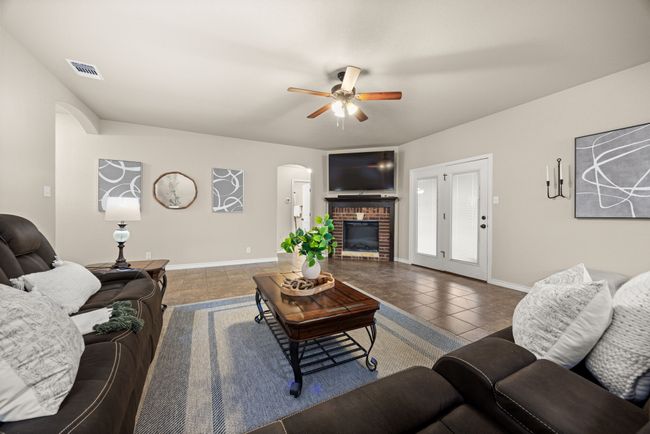 Living area with arched walkways, a fireplace, ceiling fan, and tile patterned flooring | Image 7