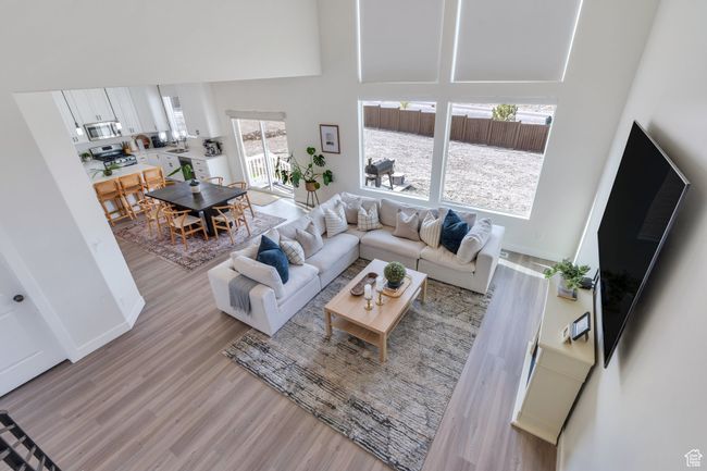 Living area with a towering ceiling, light wood-type flooring, and baseboards | Image 5