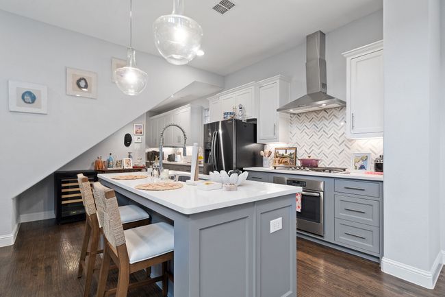 Kitchen with backsplash, light countertops, wall chimney exhaust hood, stainless steel oven, and dark wood-style floors | Image 6