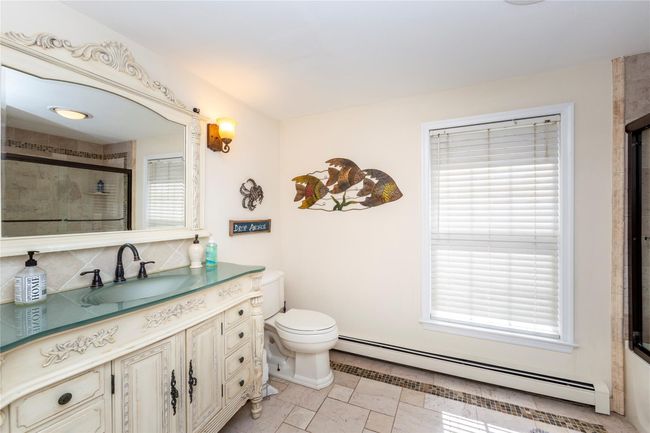 Hall Full bath featuring vanity, a baseboard heating unit, a tile shower, and toilet | Image 30