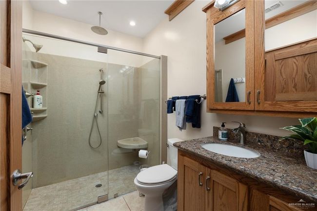 Bathroom featuring tile patterned flooring, vanity, toilet, and a shower with door | Image 11