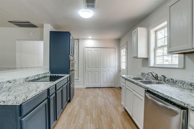 Kitchen featuring dishwasher, black electric stovetop, light wood finished floors, and light countertops | Image 9
