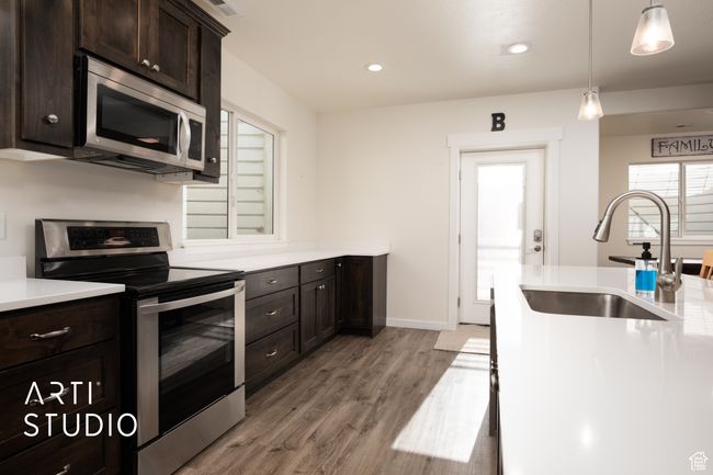 Kitchen with sink, decorative light fixtures, dark brown cabinets, light hardwood / wood-style flooring, and appliances with stainless steel finishes | Image 32