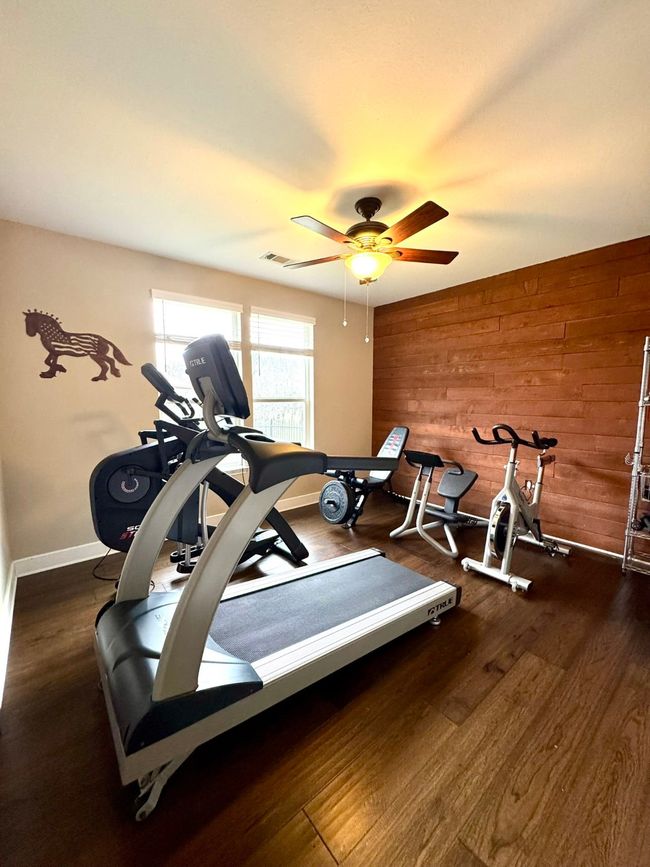 Exercise room featuring visible vents, wooden walls, baseboards, ceiling fan, and wood finished floors | Image 19