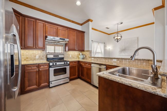 Kitchen featuring granite countertops, a gas range, stainless steel appliances, and ample cabinet space | Image 12