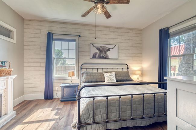 Bedroom with wood finished floors, a fireplace, and ceiling fan | Image 16