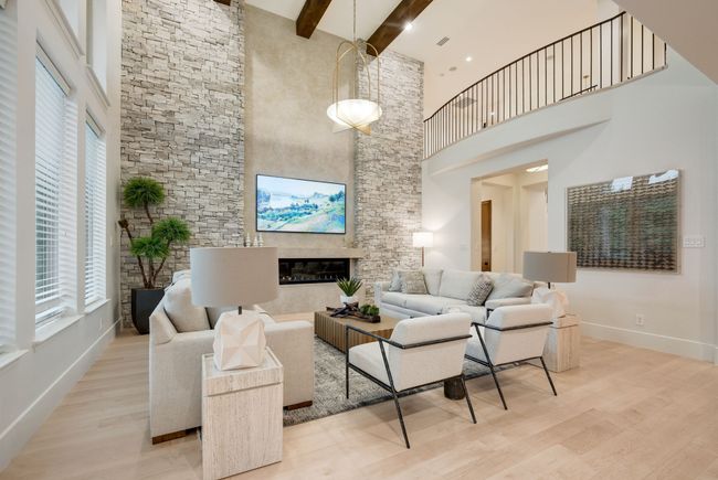 Living area featuring a towering ceiling, healthy amount of natural light, beam ceiling, wood finished floors, and baseboards | Image 6