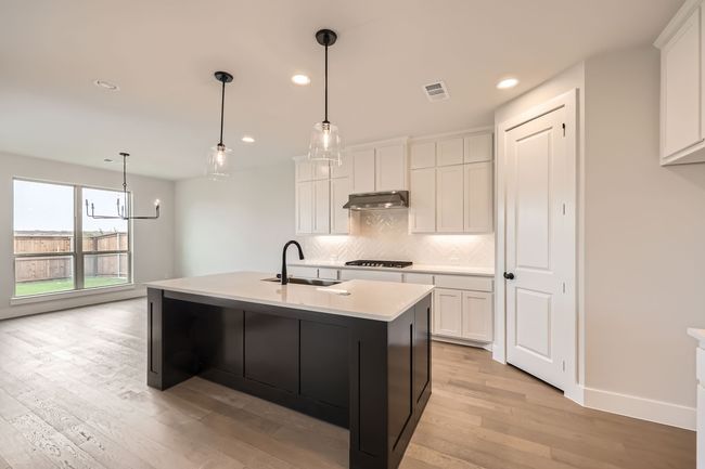 Kitchen featuring backsplash, a sink, gas cooktop, under cabinet range hood, and visible vents | Image 9