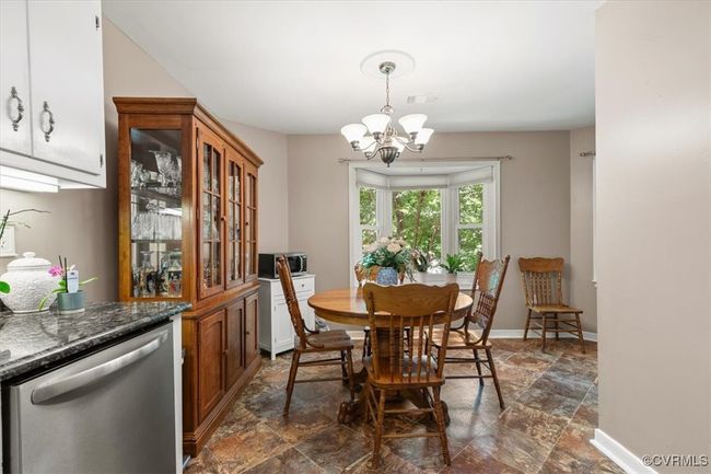 Dining area with dark stone finish floors, a chandelier, and baseboards | Image 15